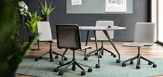 Besprechungstisch mit vier Bürostühlen auf einem grünlichen Teppich