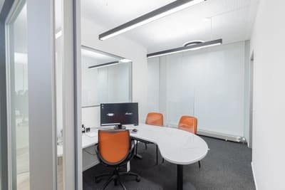 Einblick in einen Büroraum mit großem abgerundetem Schreibtisch, vor welchem zwei Besucherstühle stehen