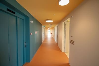 Farbenfroher Flur im Wohnheim LIV, Türen zu den Zimmern, sowie ein Aufzug